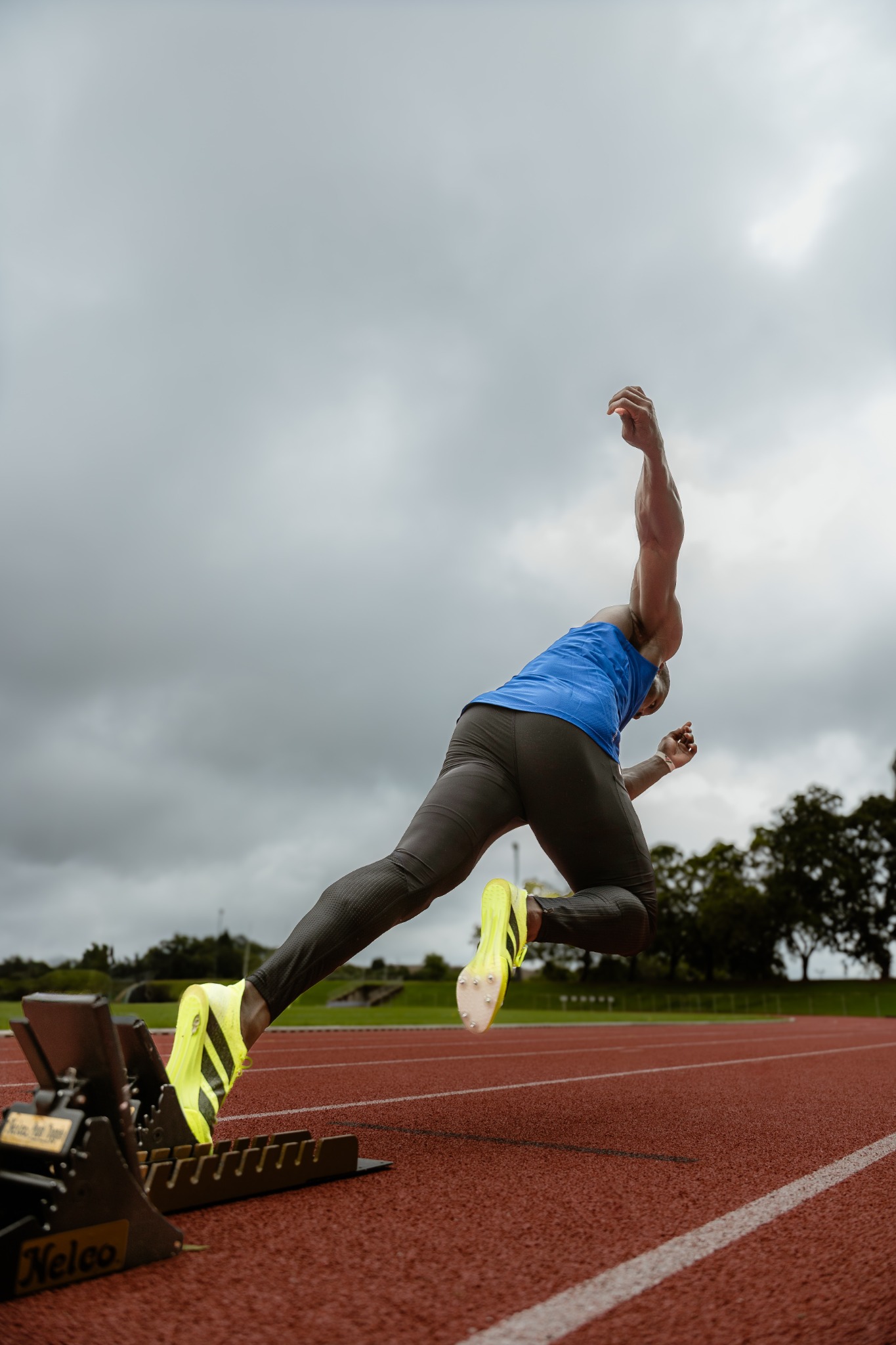 Ferdinand Omanyala launching from starting blocks on an outdoor running track